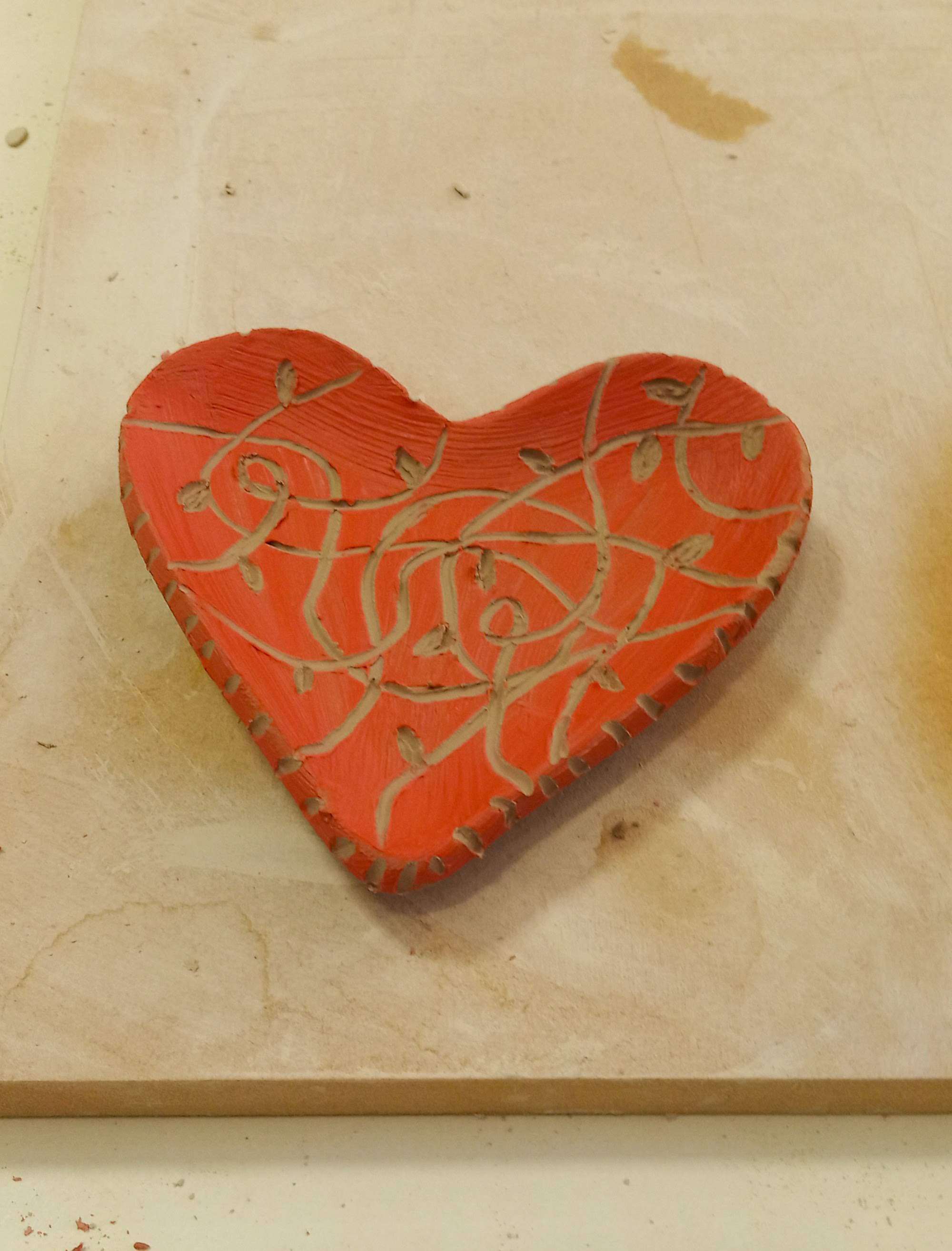 Pequeño platito con forma de corazón, pintado con engobe rojo y esgrafiado en su superficie de forma aleatoria